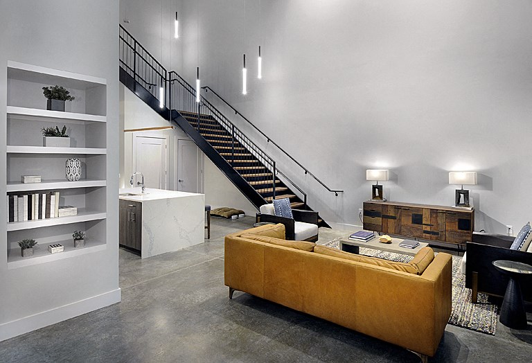 a living room with a yellow couch and a staircase