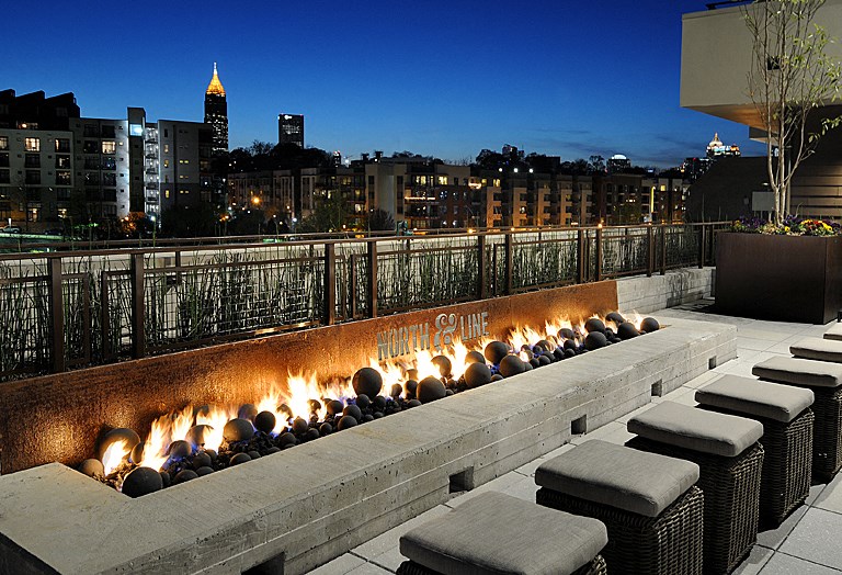 a fire pit on the rooftop of a building with a city in the background
