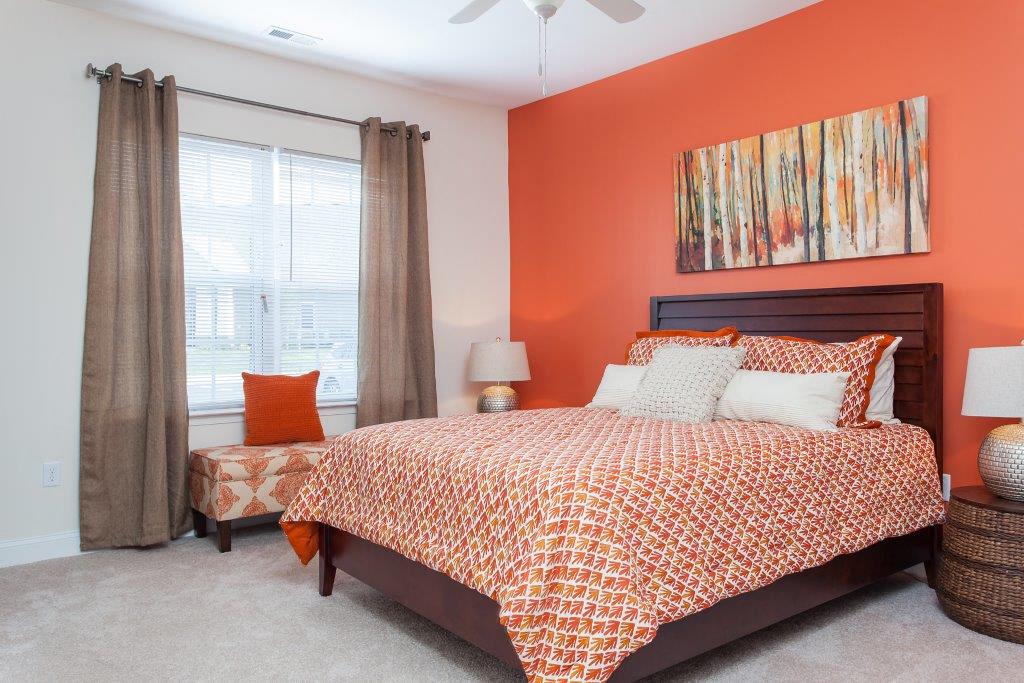 a bedroom with an orange accent wall and a bed