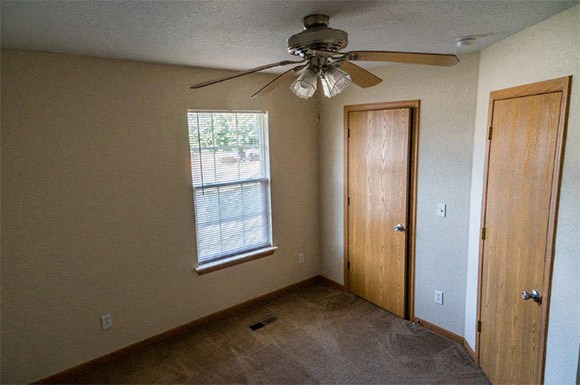 a living room with a ceiling fan and a door