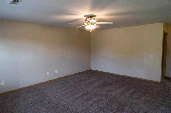 an empty living room with a ceiling fan
