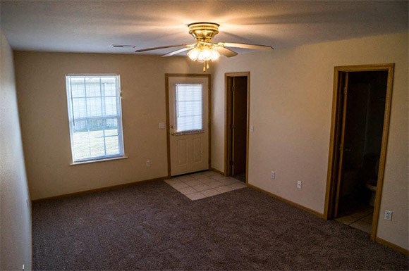 an empty living room with a ceiling fan and a door