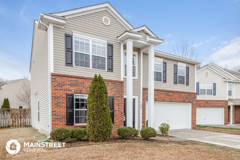 a house with two white columns on the front and a brick driveway