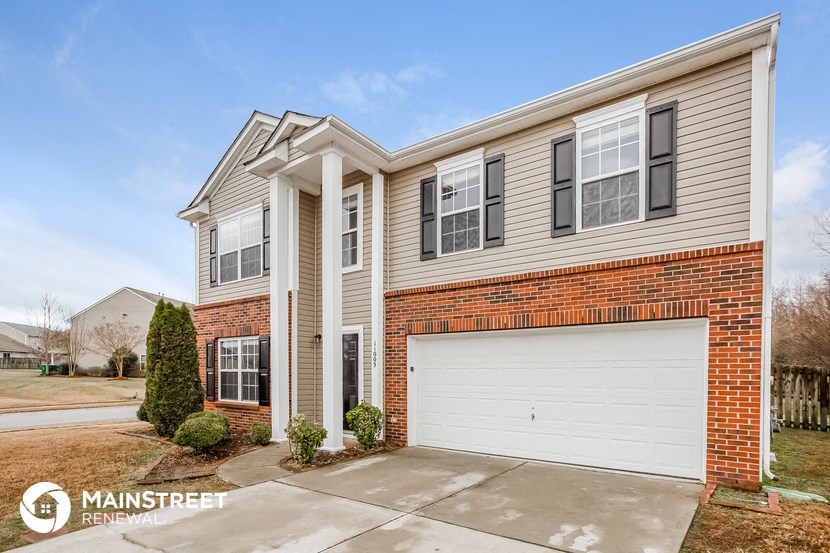 a home with a white garage door in front of a brick house