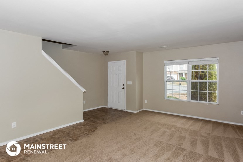 the living room of a house with a white door and a window