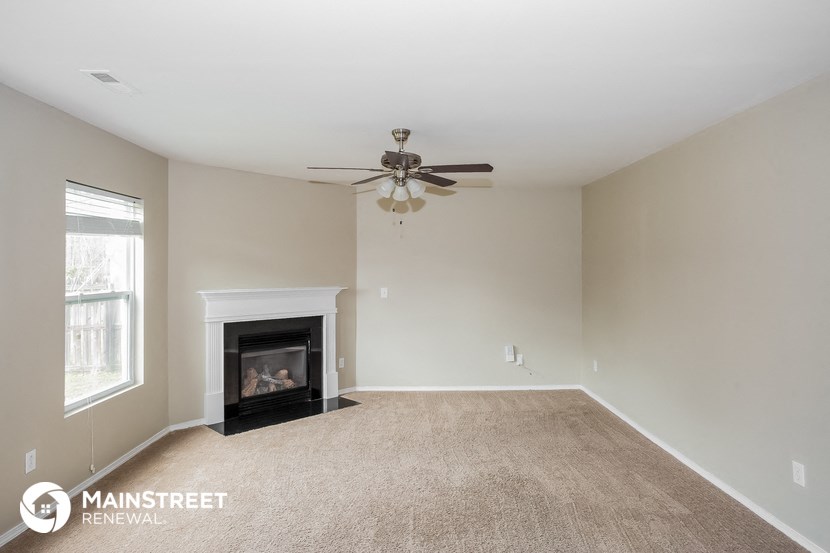 the living room has a fireplace and a ceiling fan