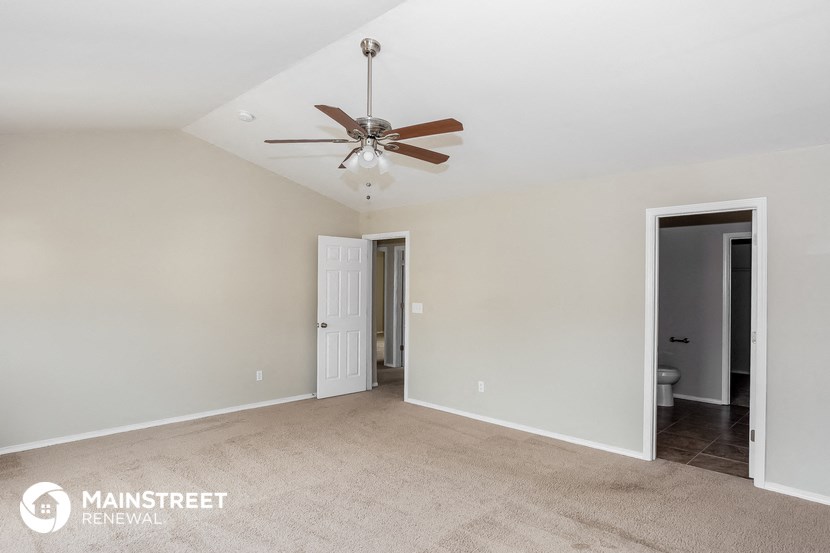 a living room with a ceiling fan and a door to a bathroom