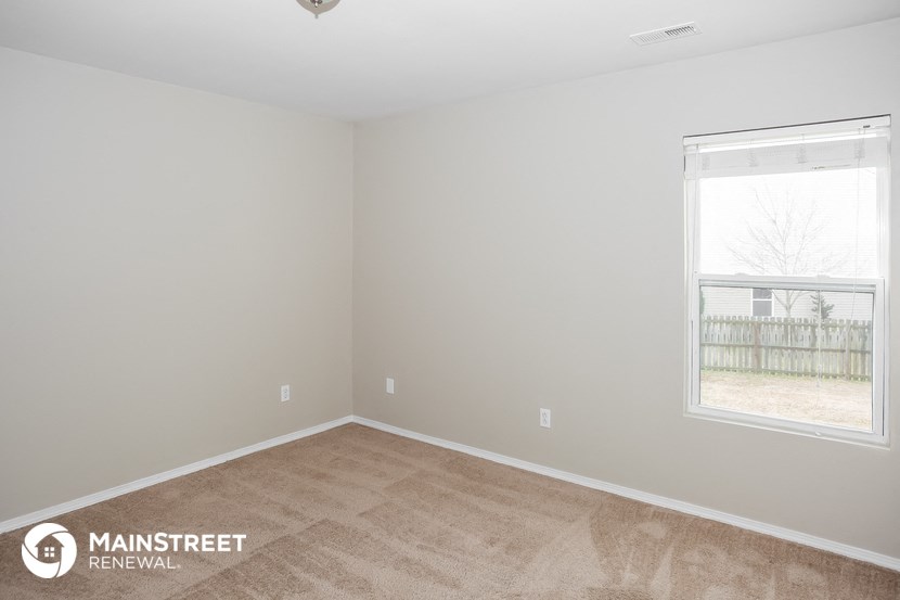 the bedroom of a small house with a wooden floor and a window