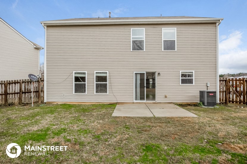 the back of a house with a yard and a wooden fence