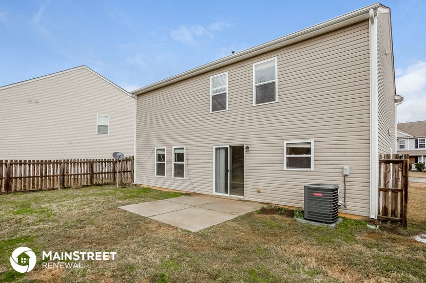 the back of a house with a yard and a trash can