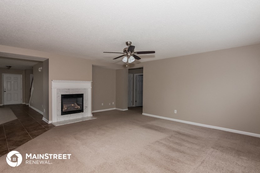 a living room with a fireplace and a ceiling fan