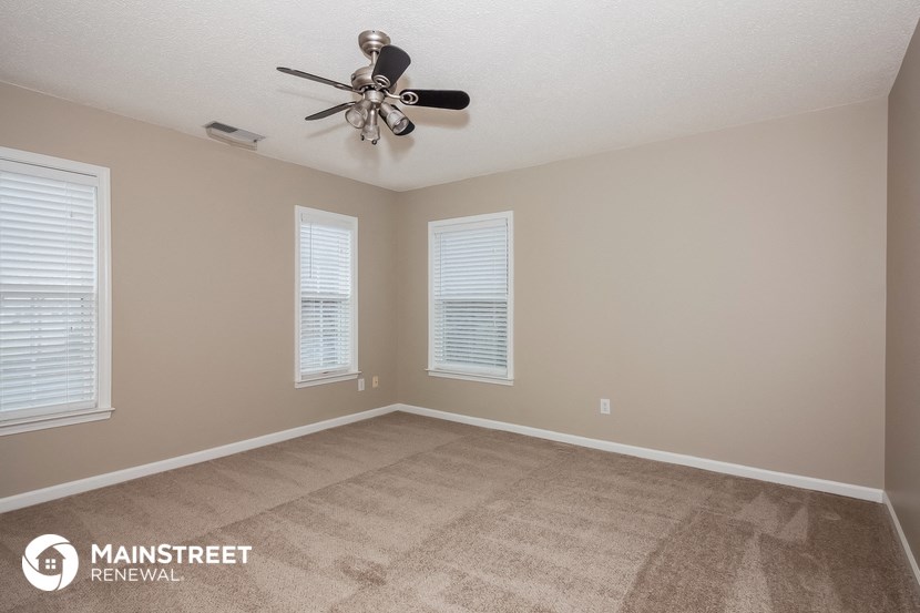 the spacious living room with carpet and a ceiling fan