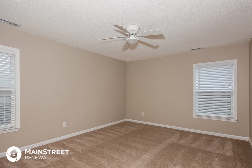 the spacious living room with a ceiling fan