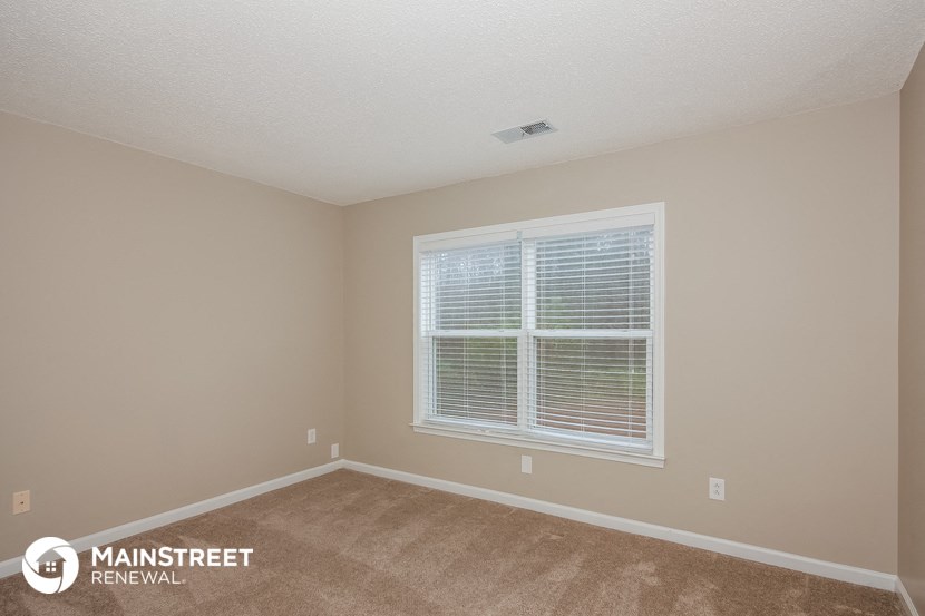 the interior of a bedroom with a large window and beige carpet