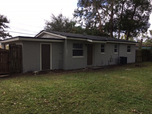 a small gray house with a yard and a fence