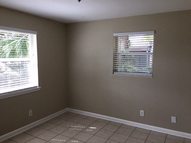 a empty room with two windows and a tiled floor