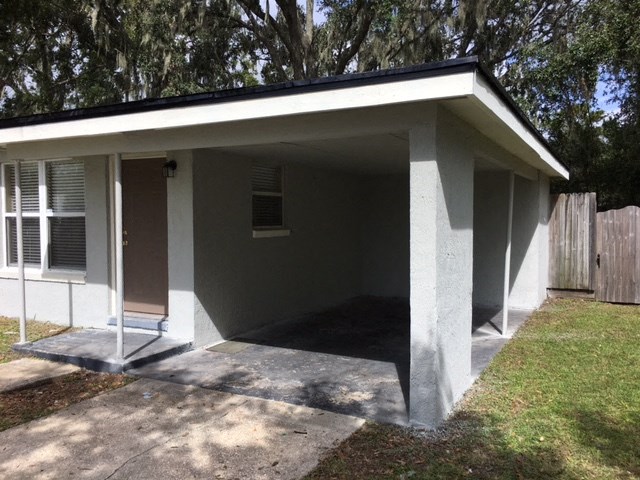 a small gray shed with a porch in a yard