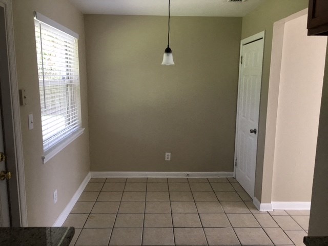 an empty kitchen with a tiled floor and a window