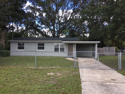 a small house in a fenced in yard with a chain link fence