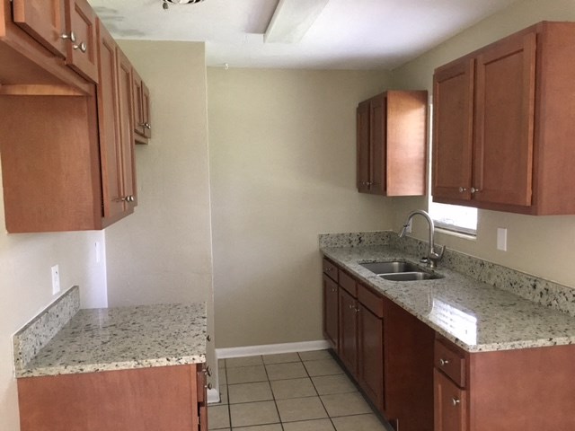 a kitchen with granite counter tops and wooden cabinets