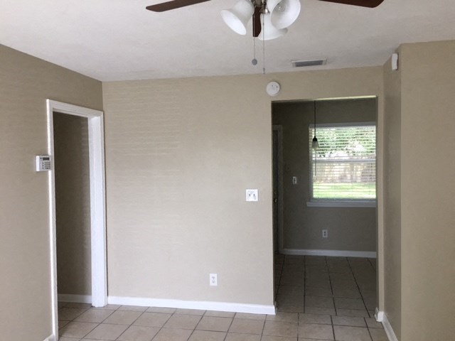an empty living room with a ceiling fan and a window