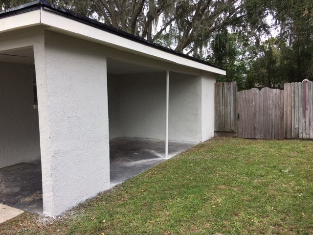 a garage with the door open in a yard with a fence