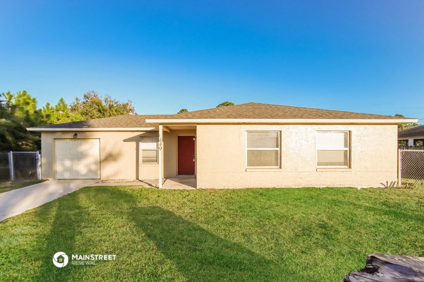 a beige house with a grassy yard and a driveway
