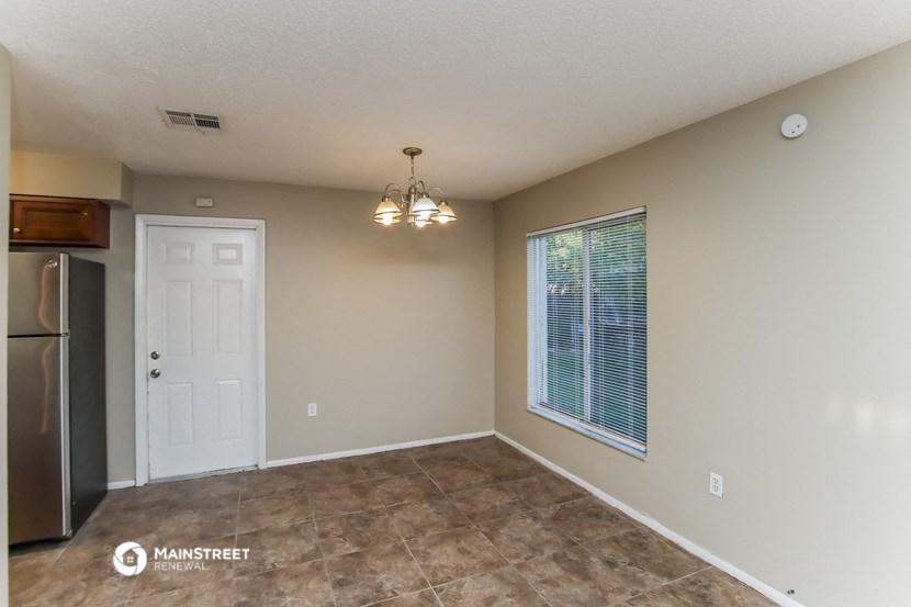 an empty living room with a refrigerator and a window