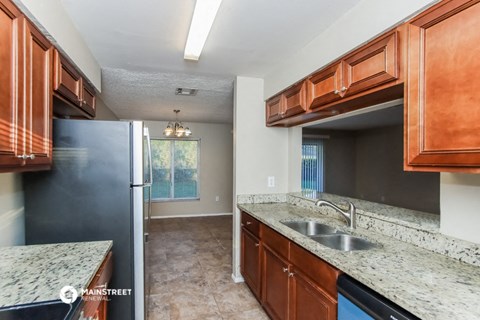 a kitchen with wood cabinets and granite counter tops and a stainless steel refrigerator