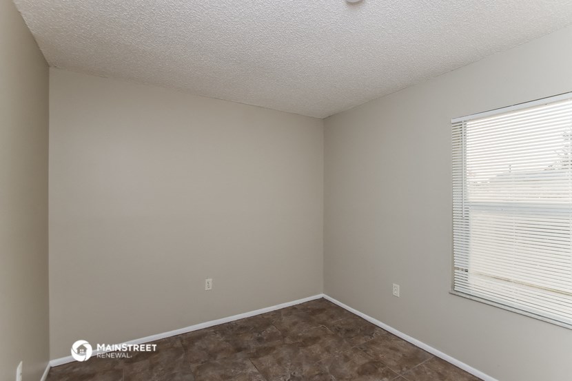 a bedroom with a large window and brown flooring