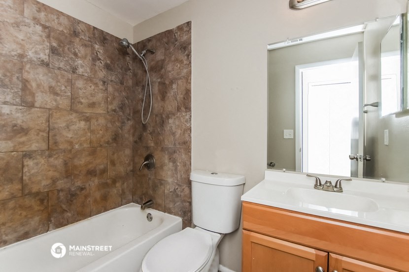 a bathroom with a tub toilet and sink and a mirror