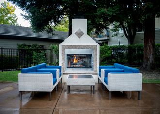 the outdoor living area has a fireplace and blue couches