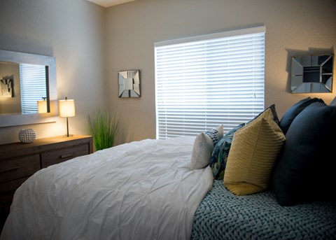 a bedroom with a bed with pillows and a dresser and a window