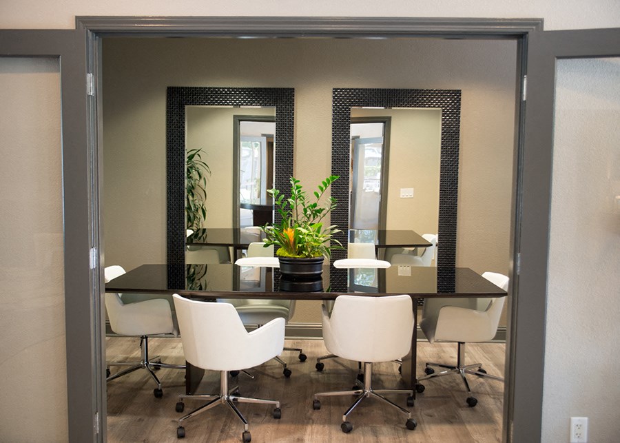 a conference room with a table with chairs and mirrors