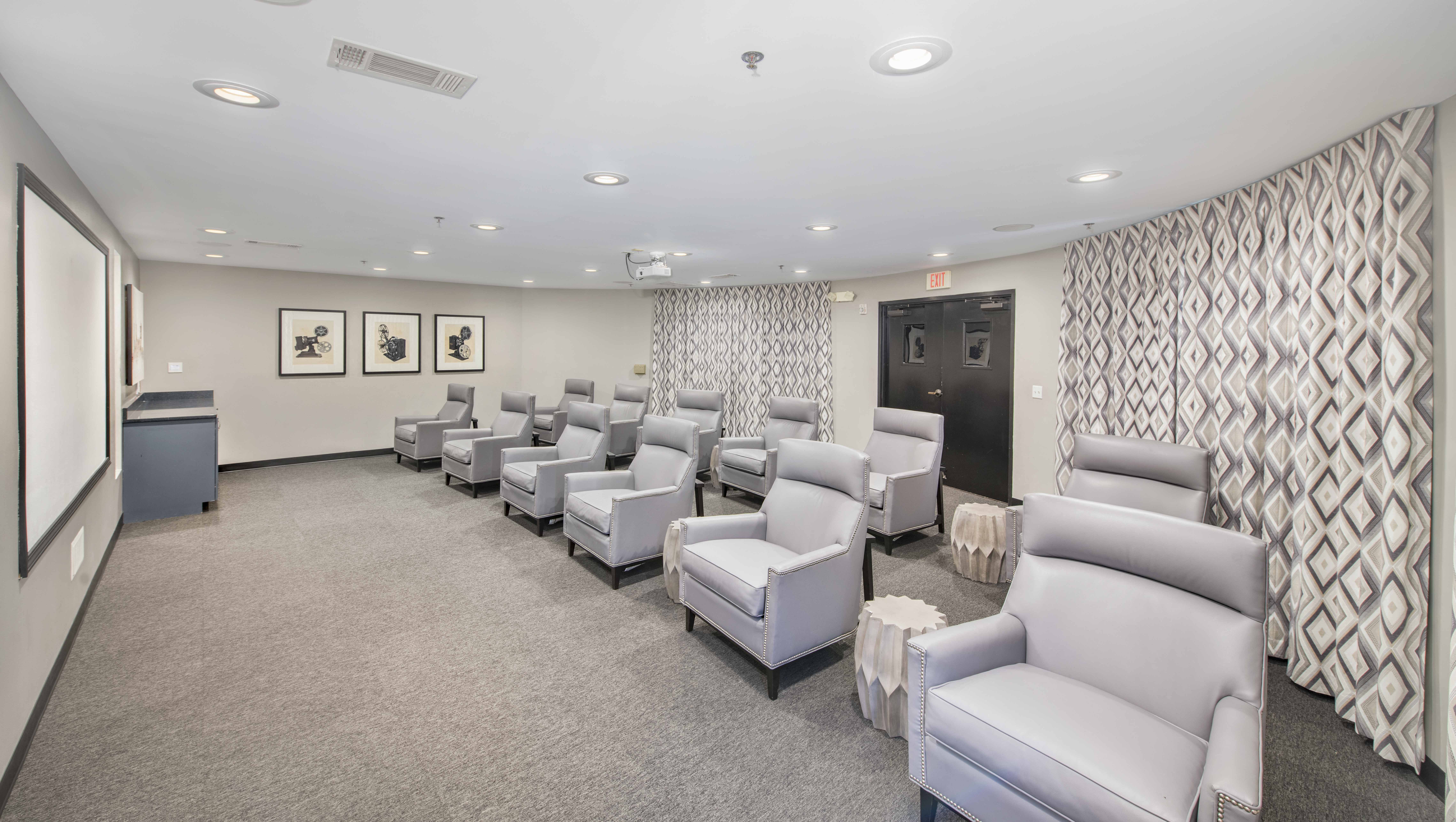 a theater room with white chairs and a white and black wallpaper