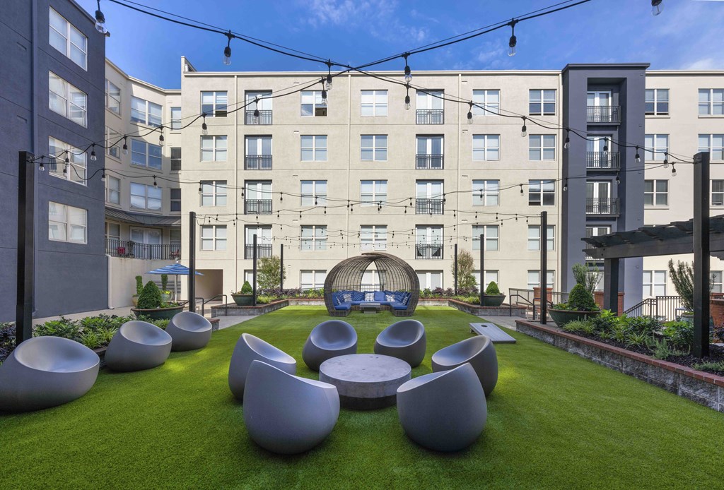 a courtyard with a lawn and a table and chairs in front of an apartment building