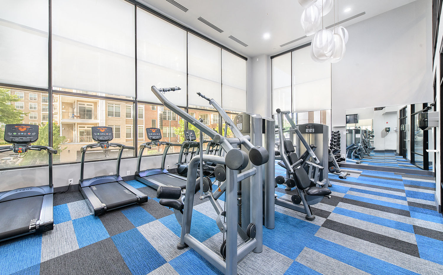 a gym with cardio equipment and windows at the district flats apartments