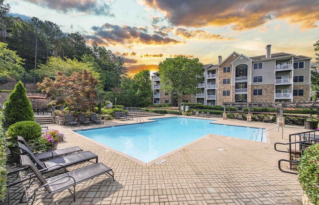 an outdoor swimming pool with a sunset over an apartment building