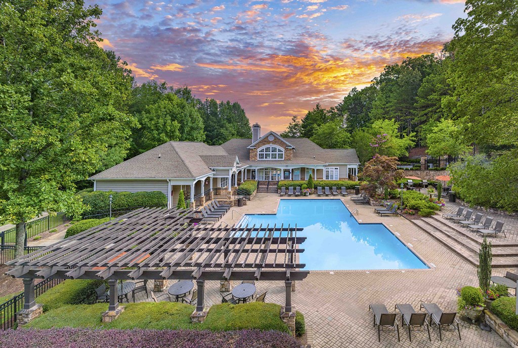an aerial view of a pool with chairs and a house in the background