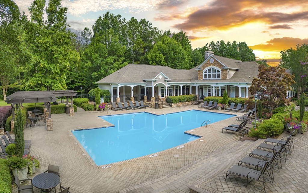 a swimming pool with a house and chairs around it