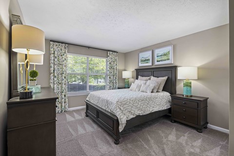 A bedroom with a large bed, nightstands, and a window with curtains.