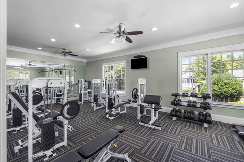 A spacious gym with a variety of equipment and a ceiling fan.