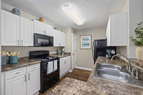 A kitchen with black appliances and granite countertops.