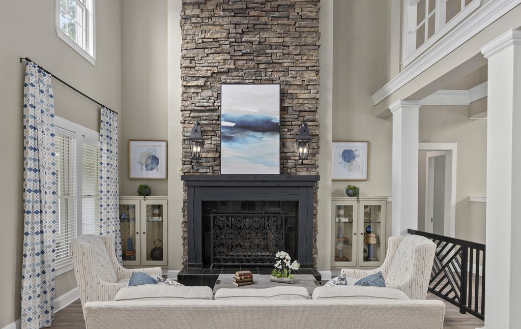 A living room with a stone fireplace and a painting above it.