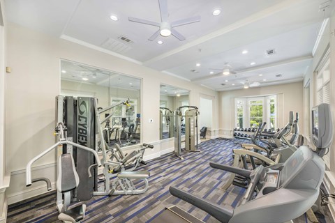 a gym with cardio equipment and mirrors on the wall
