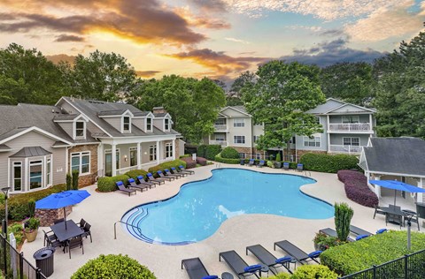 an aerial view of an outdoor pool with chairs and umbrellas and a house