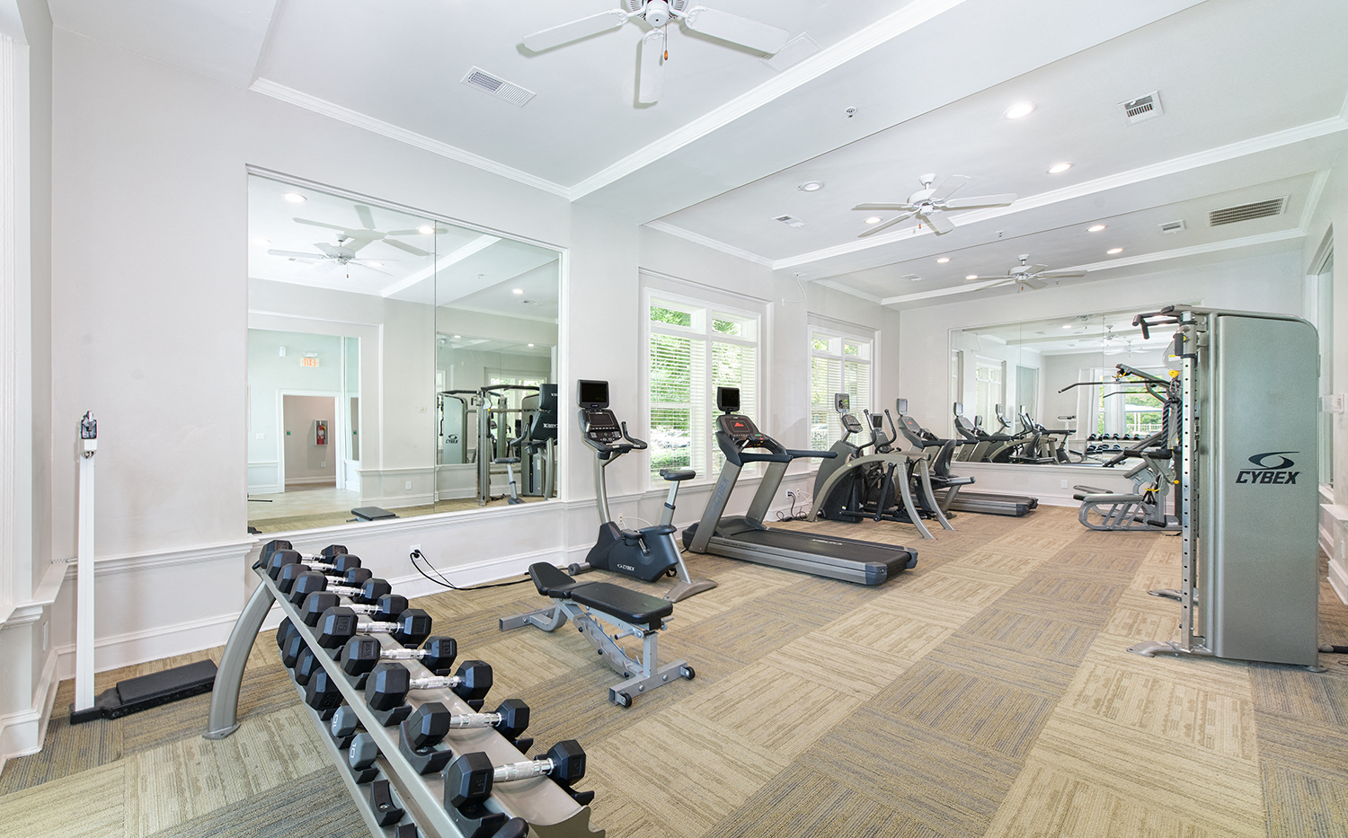 a gym with cardio equipment and mirrors in a home for sale