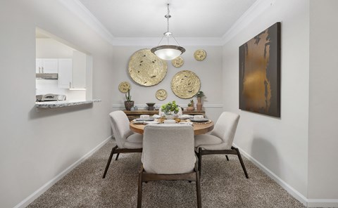 a dining room with a table and chairs and a kitchen in the background
