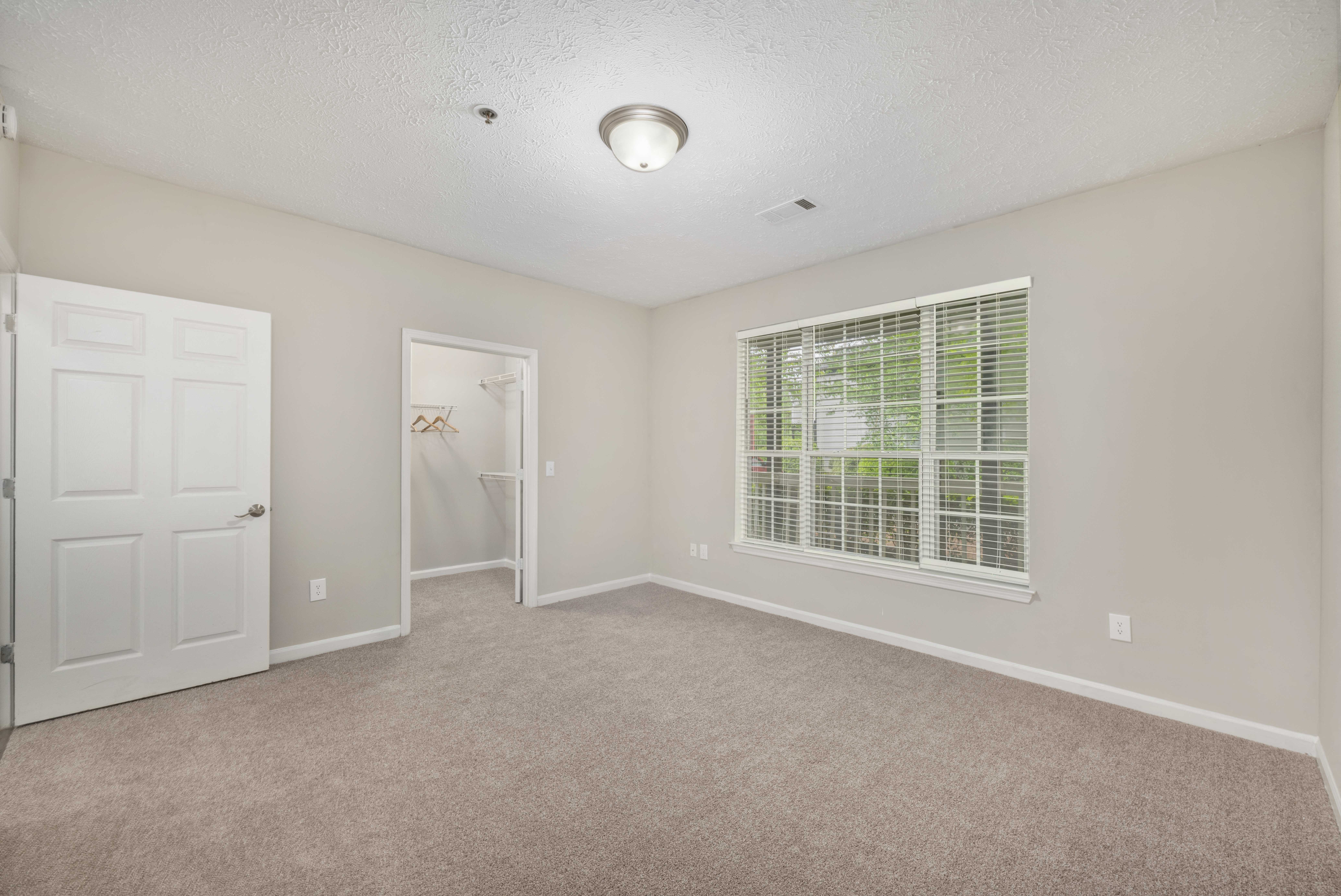 an empty living room with a large window and a white door