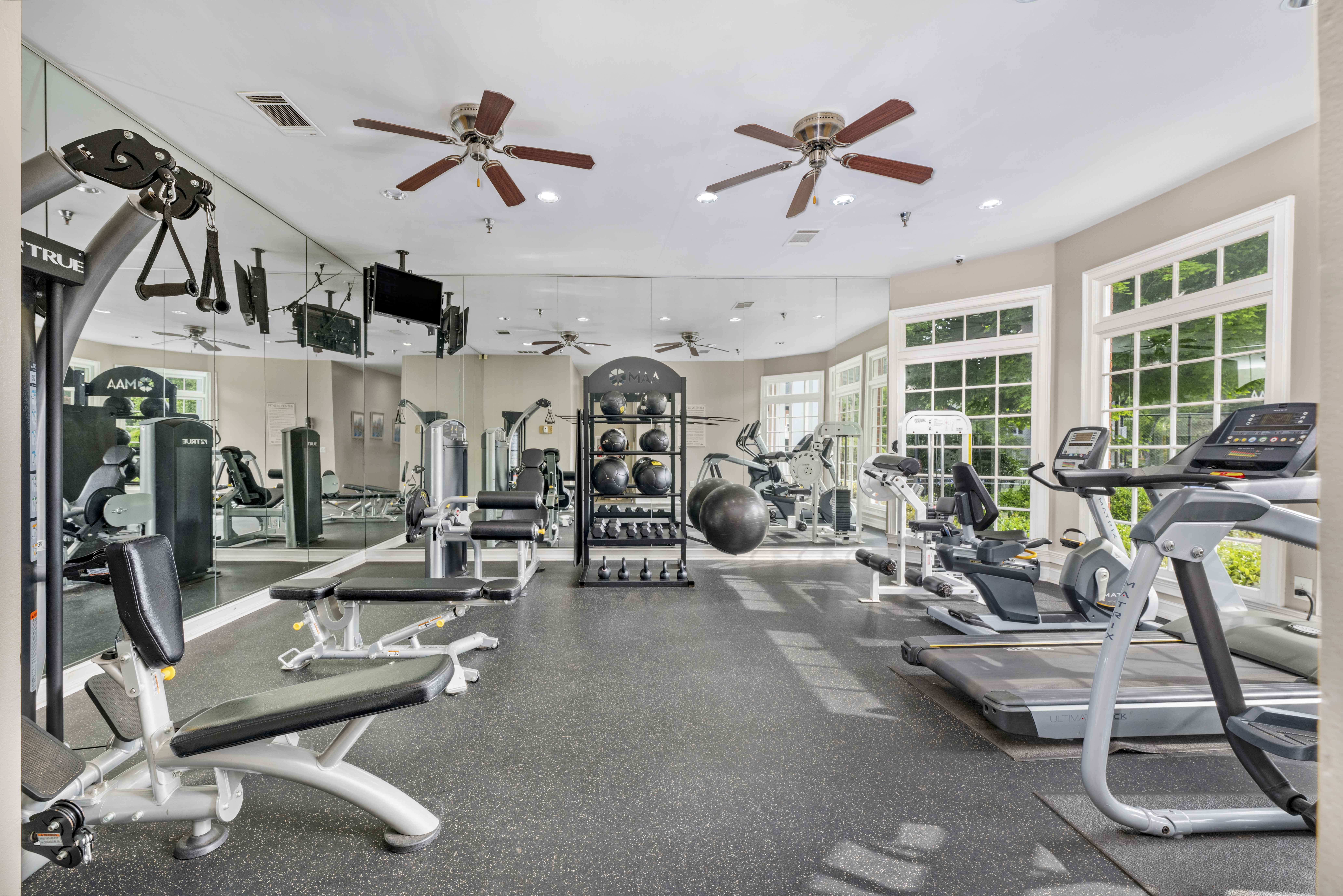 a gym with weights and cardio equipment and ceiling fans
